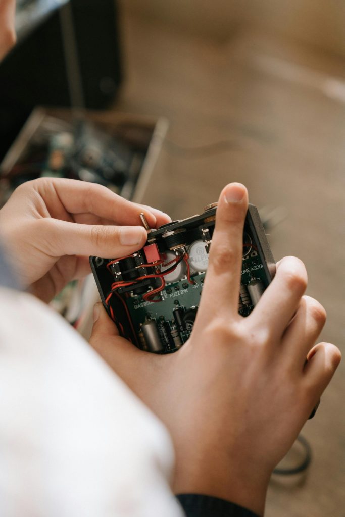 Close-up of hands repairing an electronic circuit board indoors, demonstrating electronics engineering.