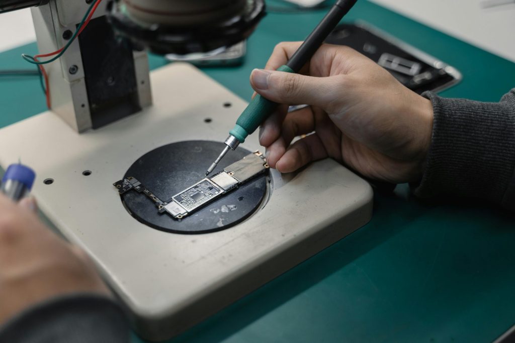 Detail view of hands soldering a circuit board in an electronics workshop.