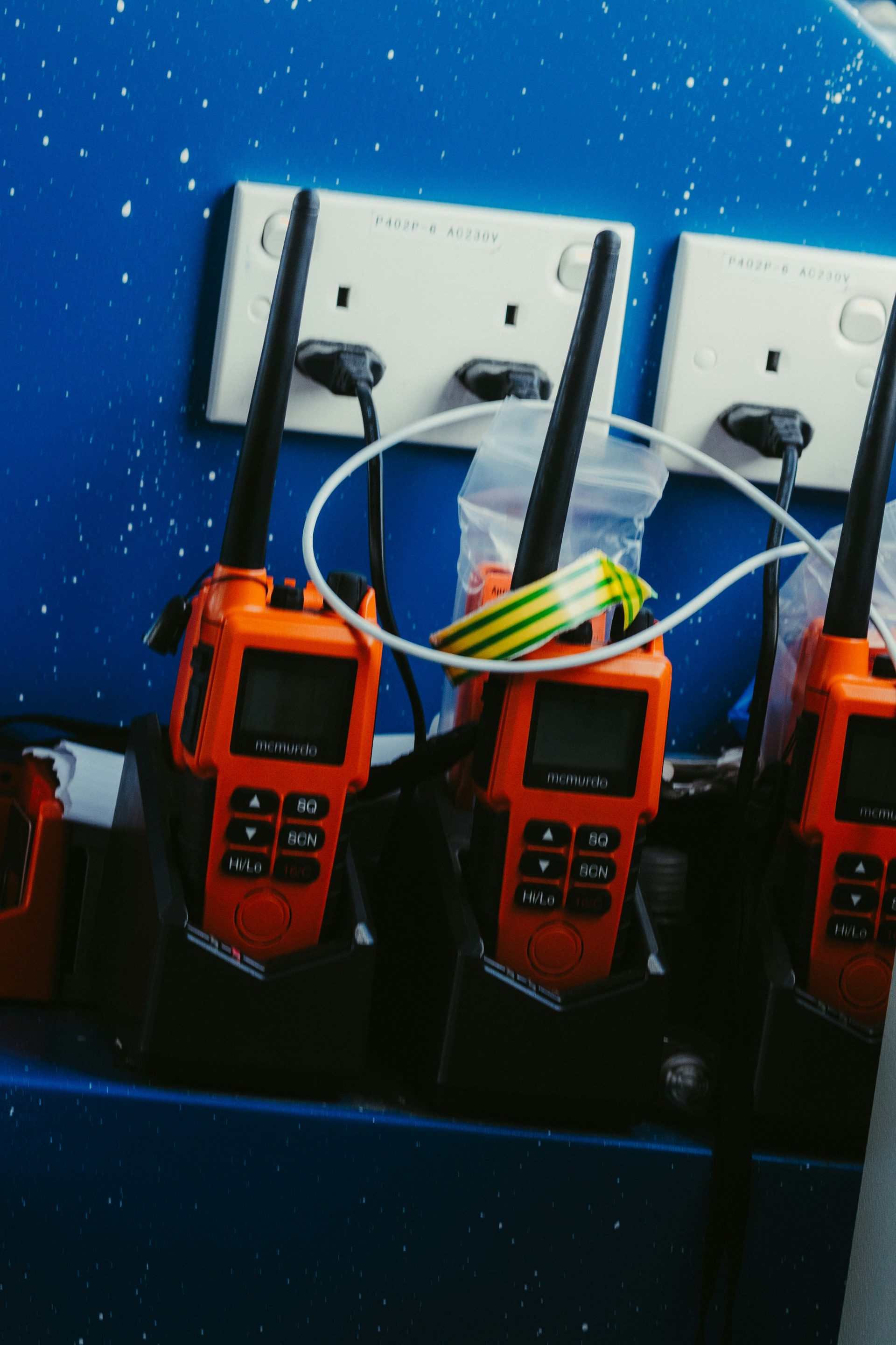 Orange walkie-talkies charging on a blue surface.